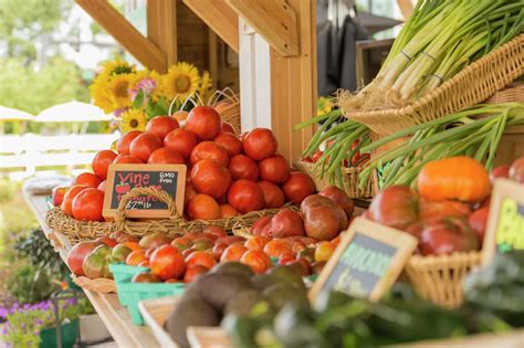Farmers market stand with tomatoes, sunflowers, and green onions
